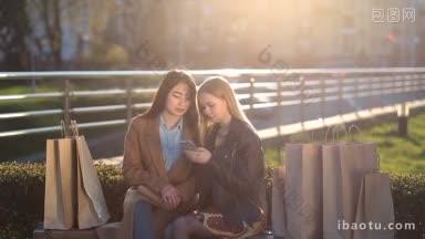 两个美丽的多民族女友坐在长凳上，周围有许多购物袋在社交网络发短信的朋友